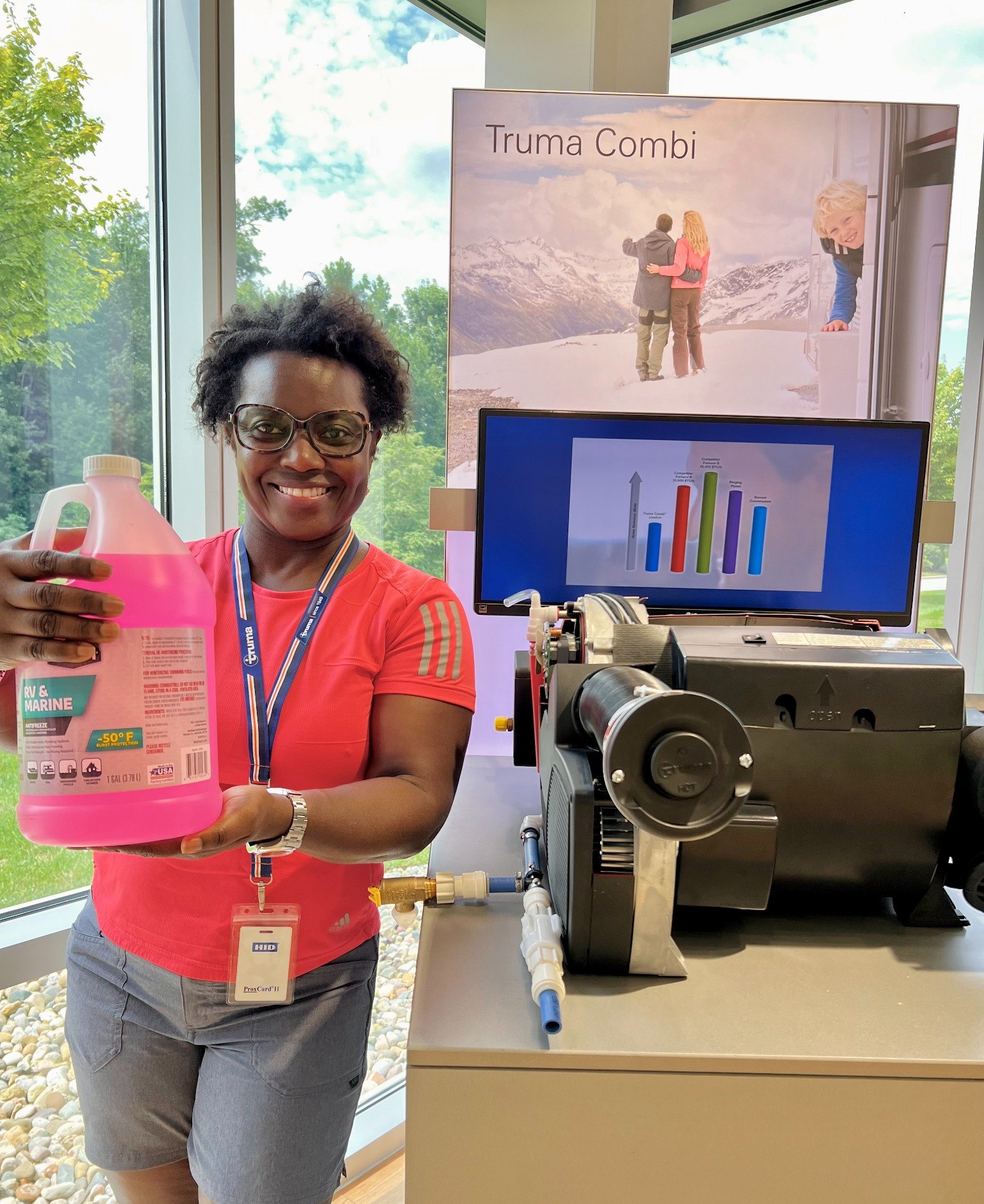 Lola holding RV antifreeze beside a Truma Combi display at Truma North America headquarters
