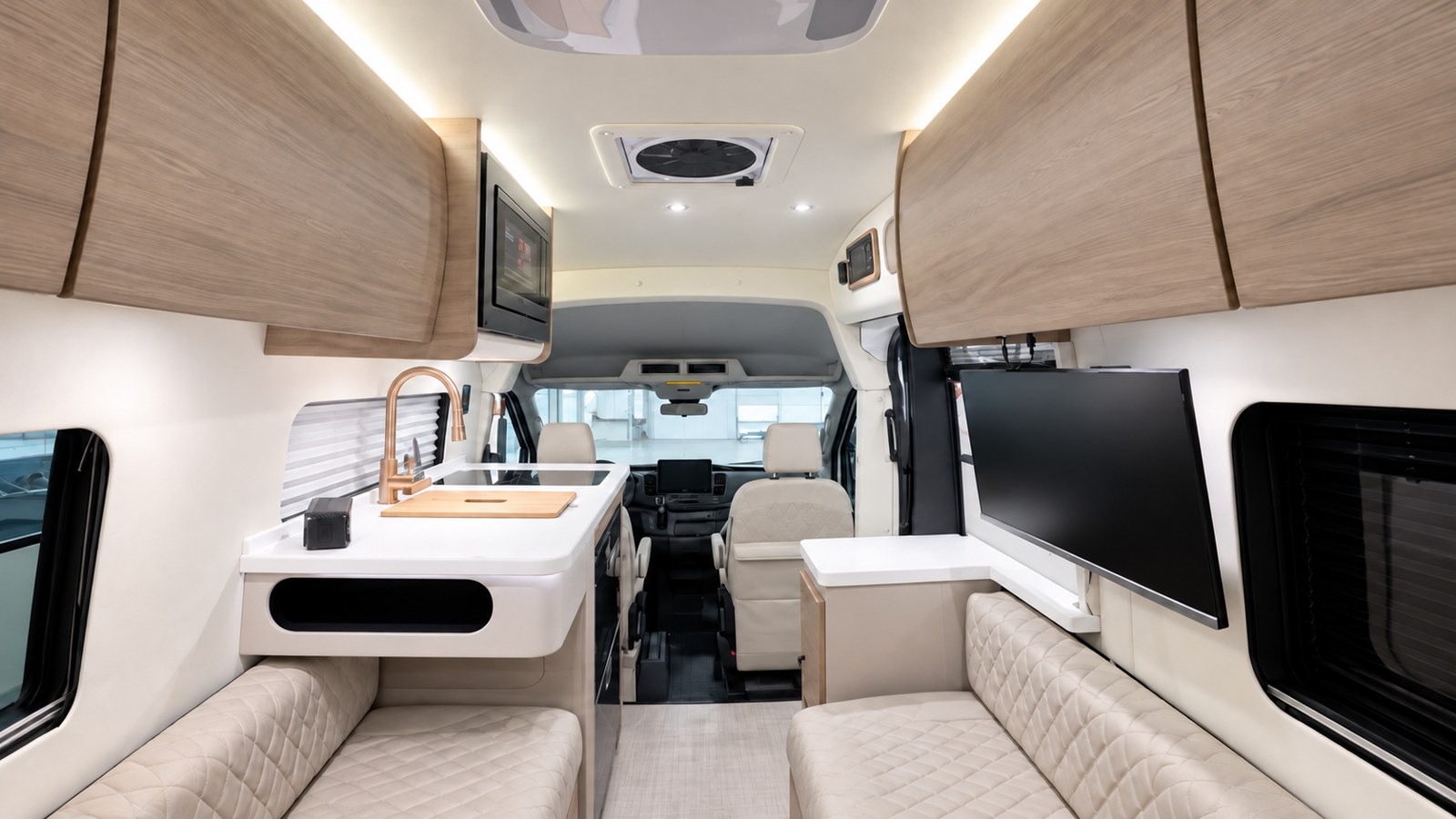 A view toward the cab shows the opposing lounges, galley, television, and light Driftwood cabinetry.